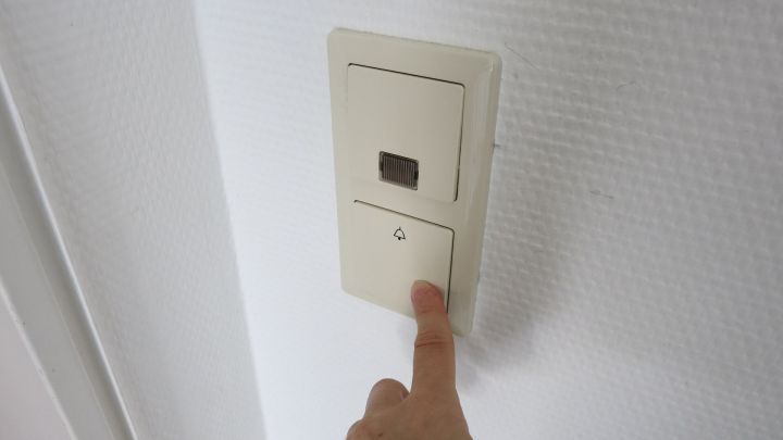 Finger dr&uuml;ckt T&uuml;rklingelknopf an wei&szlig;er Wand, symbolisiert ungebetenen Besuch loswerden durch Bet&auml;tigung der Klingel.