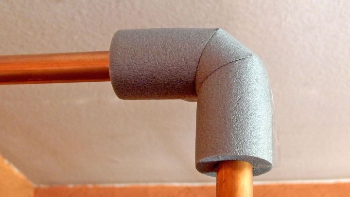 Ein graues Rohrisoliermaterial umschlie&szlig;t ein Kupferrohrbiegung, um eine effiziente D&auml;mmung zu gew&auml;hrleisten.
