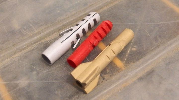 Drei D&uuml;bel liegen auf einer Oberfl&auml;che, bereit f&uuml;r die Installation in einem Bauprojekt, zeigen verschiedene Formen und Farben.