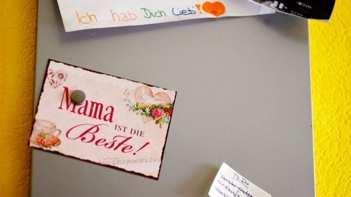 Eine graue Magnetwand aus Eisenplatte h&auml;lt Notizen und Fotos in einem freundlichen, gelben Raum.