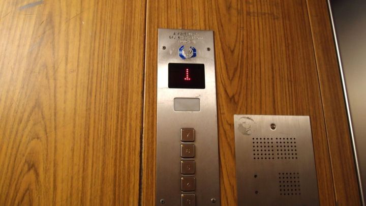 Ein Aufzug mit Holzw&auml;nden zeigt das Bedienfeld, das auf den ersten Stockwerk hinweist. Langweile im Fahrstuhl.