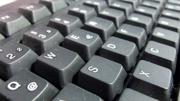 Eine verschmutzte Tastatur liegt im Fokus, deren Tasten leicht schmutzig sind, was auf Pflegebedarf hinweist.