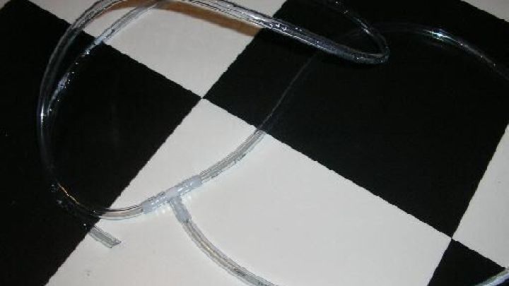 Durchsichtige Schl&auml;uche liegen auf einem schwarz-wei&szlig;en Schachbrettmusterboden, gewunden zu einer potenziellen Pumpe.