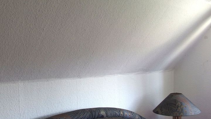 Ein Raum mit schr&auml;ger Wand und einem Bett im Vordergrund, w&auml;hrend ein Lichtstrahl von der Seite f&auml;llt.