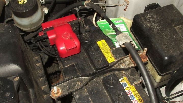 Eine Autobatterie liegt in einem Fahrzeugmotor, w&auml;hrend Kabel angeschlossen sind, um die leere Batterie aufzuladen.