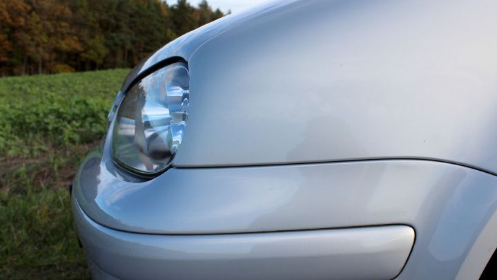 Ein silberner PKW wird mit Motor&ouml;l behandelt, um die Kunststoffteile in der gr&uuml;nen Landschaft auffrischen.