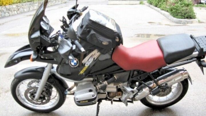 Ein schwarzes Motorrad mit rotem Sitz steht auf einem befestigten Parkplatz, bereit f&uuml;r Lackentfernung ohne Abschleifen.