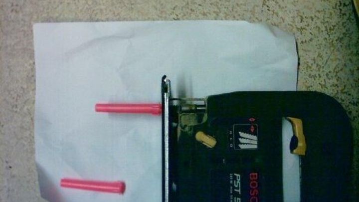 Stichs&auml;ge mit S&auml;geblattschutz auf Papier; rote Stifte dienen als Schutz. Etikett: "BOSCH PST 54 PE" am Ger&auml;t.