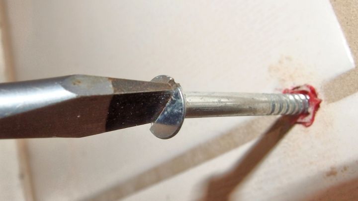 Ein Schraubendreher dreht eine Schraube mit Fett in ein Loch in einer Wand, erleichtert das Hineindrehen.