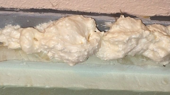 Bauschaum liegt unordentlich auf einer Fl&auml;che, m&ouml;glicherweise beim Einsatz im Bau, und ben&ouml;tigt Reinigung von der Haut.