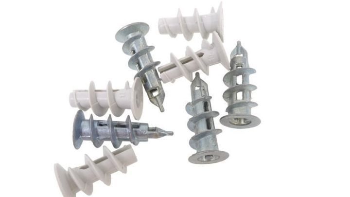 Metall- und Kunststoff-D&uuml;bel liegen auf wei&szlig;em Hintergrund, bereit zur Verankerung in Rigipsplatten.