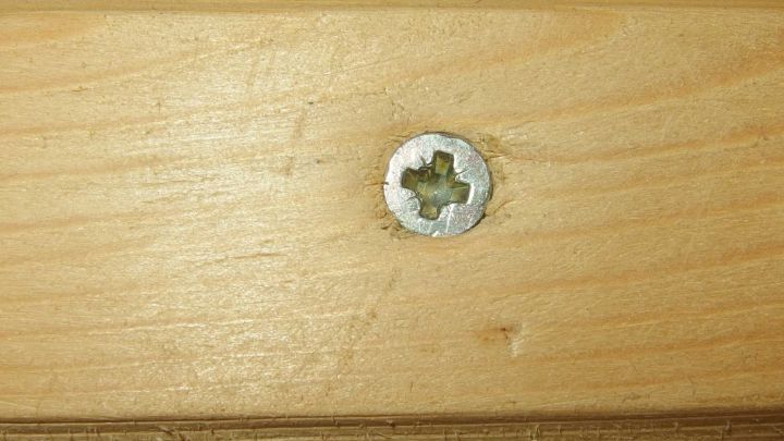 Eine Schraube sitzt fest in einem Holzst&uuml;ck, w&auml;hrend sie in die Holzoberfl&auml;che eingeschraubt wird, um Holzspaltung zu vermeiden.