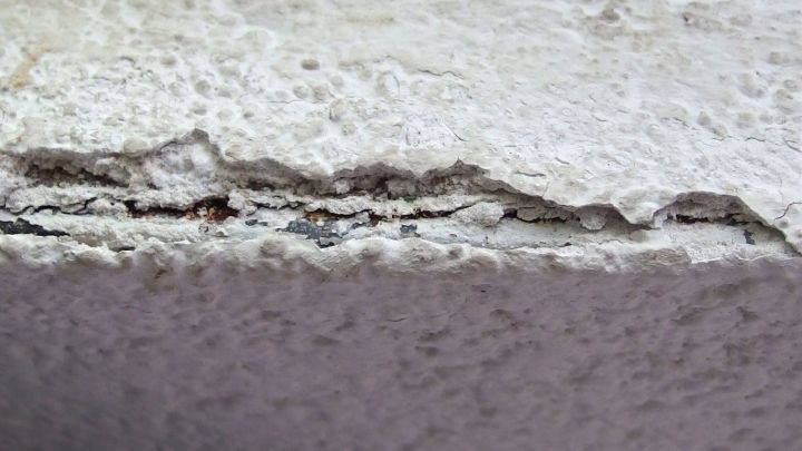 Eine besch&auml;digte Wandstelle zeigt Risse und lose Bereiche, die mit Gips verputzt werden m&uuml;ssen, um die Oberfl&auml;che zu reparieren.