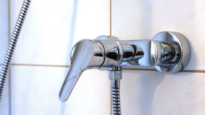 Ein gl&auml;nzender Wasserhahn wird mit Teflonband abgedichtet, um Gewindeverbindungen gegen Leckagen zu sichern.