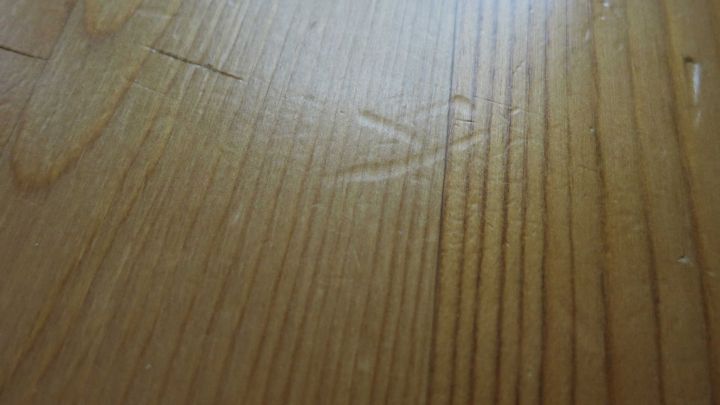 Kleine Dellen im Holz sind sichtbar, die die nat&uuml;rliche Maserung des Holzes st&ouml;ren. Der Boden ist hell und glatt.