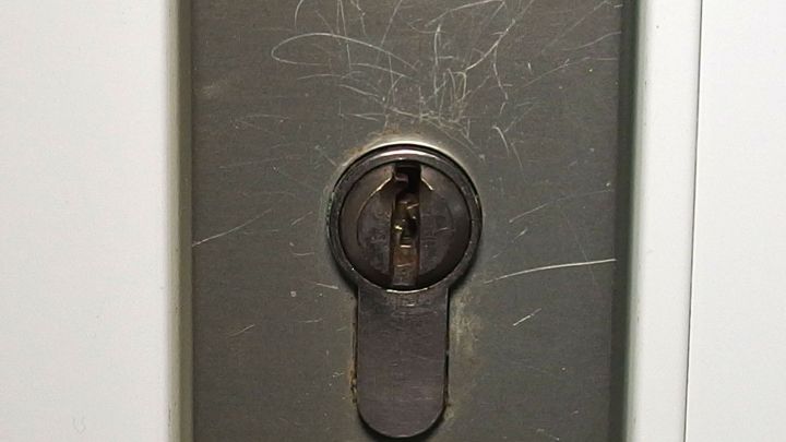 Ein Zylinderschloss ist nah zu sehen, w&auml;hrend ein Schl&uuml;ssel hineingef&uuml;hrt wird, um das Schloss zu &ouml;len.