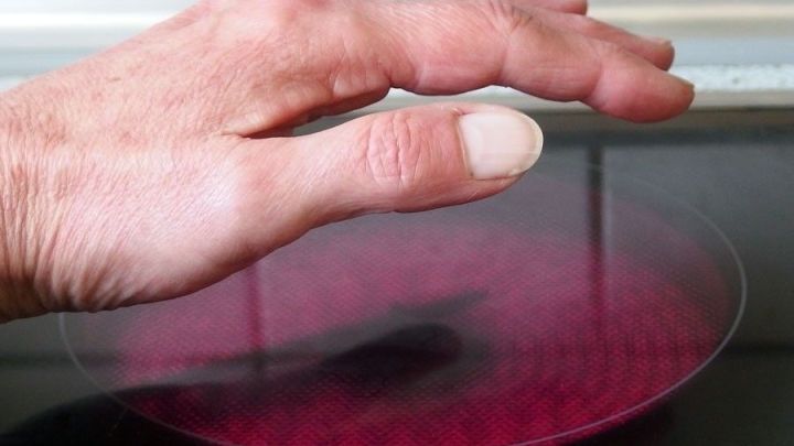 Eine Hand schwebt &uuml;ber einer rot erleuchteten Kochfl&auml;che, um Knoblauchgeruch beim Kochen schnell zu entfernen.