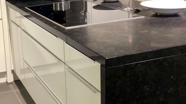 Eine moderne K&uuml;che zeigt einen Kochfeld-Einbau in der Arbeitsplatte, umgeben von eleganten M&ouml;beln und Geschirr.