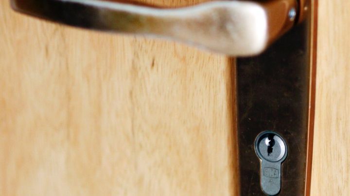 Ein Schwerg&auml;ngiges T&uuml;rschloss ist nah zu sehen, w&auml;hrend jemand den T&uuml;rgriff bet&auml;tigt, um die T&uuml;r zu &ouml;ffnen.