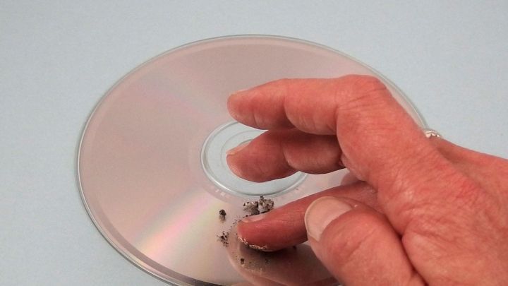 Ein Hand greift eine CD, w&auml;hrend sie in einem sanften Bewegungsrahmen poliert wird, um Kratzer zu entfernen.