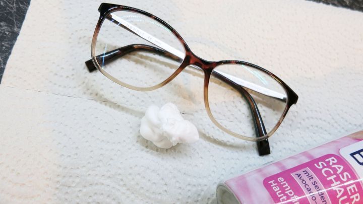 Eine Brille liegt auf einem K&uuml;chenpapier, w&auml;hrend daneben Rasiergel platziert ist, bereit zum Reinigen der Gl&auml;ser.