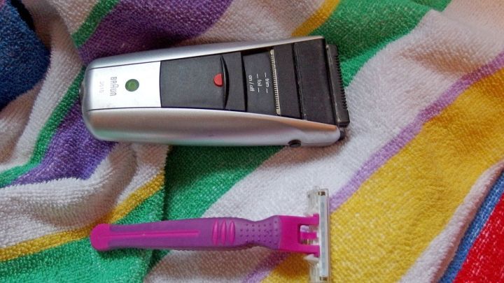 Ein Rasierapparat liegt neben einem Rasierer auf einem bunten Handtuch, bereit f&uuml;r die Rasur-Erleichterung.