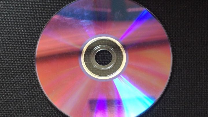 Eine CD mit Kratzern liegt auf einer dunklen Oberfl&auml;che, bereit, mit Autopolitur gereinigt zu werden.