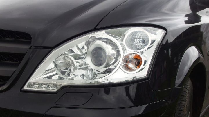 Eine schwarze Fahrzeugfront zeigt elegante Tagfahrleuchten, die im Kontext einer urbanen Umgebung gut sichtbar sind.