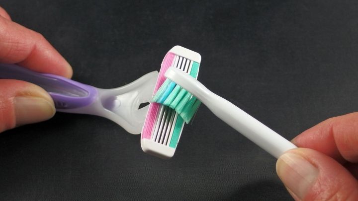 Eine Hand h&auml;lt einen Rasierer, w&auml;hrend die andere Hand eine Rasierklinge wechselt, in einem modernen Badezimmerkontext.