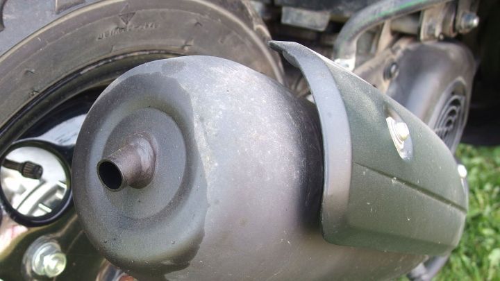 Ein Endschalld&auml;mpfer aus einem Fahrzeug, der mit Backofenspray gereinigt wird, steht im gr&uuml;nen Gras.