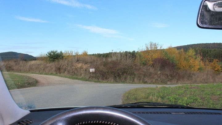 Ein Blick aus einem Auto auf eine kurvige Stra&szlig;e, w&auml;hrend sich die d&auml;mmrige Landschaft um die Fahrt herum entfaltet.