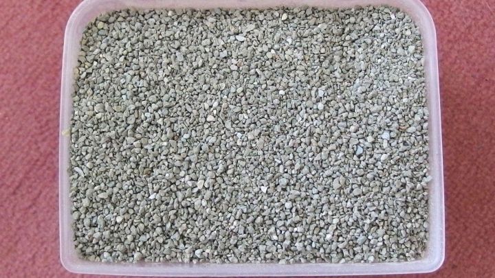 Eine Sch&uuml;ssel mit Katzenstreu steht auf einem roten Boden und absorbiert Feuchtigkeit im Auto f&uuml;r einen frischen Duft.