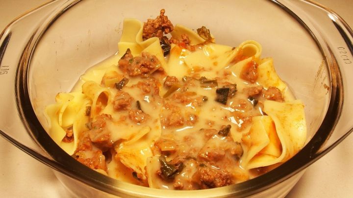 Eine transparente Sch&uuml;ssel mit einem herzhaften Auflauf aus Nudeln, Fleisch und So&szlig;e in einer neutralen K&uuml;che.