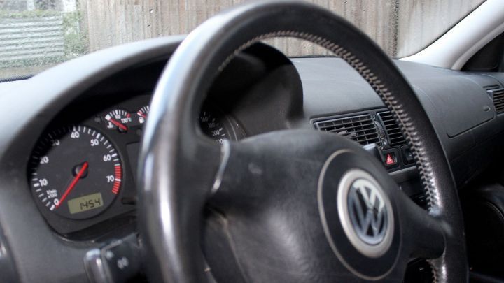 Ein Armaturenbrett mit einem Volkswagen-Logo zeigt ein Loch und das Lenkrad. Es ist in einem Fahrzeuginneren sichtbar.