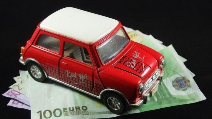 Ein rotes Modellauto liegt auf Euro-Scheinen, was die Verbindung zwischen dem Autoverkauf und Geldvisualisierung zeigt.