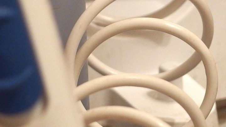 Eine Munddusche zeigt eine gewundene Schlauchleitung, die f&uuml;r die Wasserzufuhr in einem Badezimmer gedacht ist.