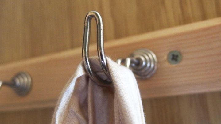 Ein silberner Haken h&auml;lt einen Stoffbeutel an einem Holzregal in einer gut organisierten Abstellkammer.