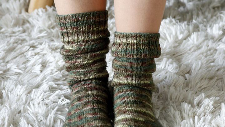 Gemusterte Socken umh&uuml;llen die F&uuml;&szlig;e, w&auml;hrend sie auf einem weichen, flauschigen Teppich ruhen.