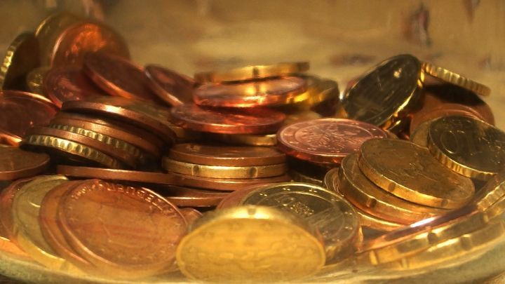 Eine Sch&uuml;ssel mit verschiedenen M&uuml;nzen liegt auf einem Tisch, die zum Sparen f&uuml;r Weihnachten oder Urlaub verwendet werden k&ouml;nnten.