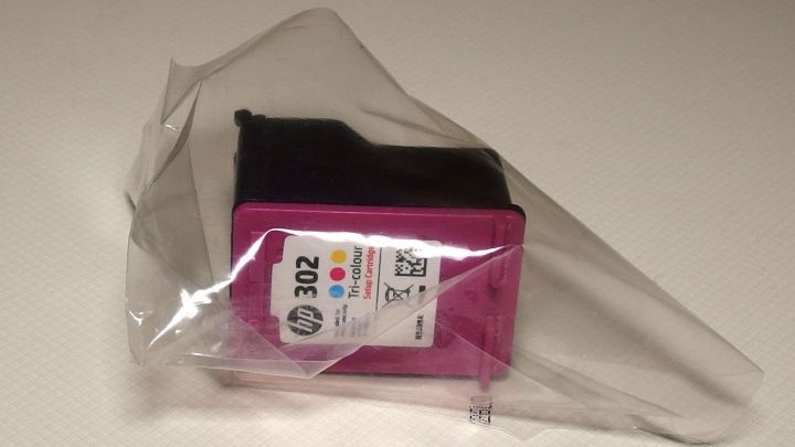 Eine Druckerpatrone in einer transparenten Verpackung liegt gesch&uuml;tzt auf einer glatten Oberfl&auml;che, bereit zur Verwendung.