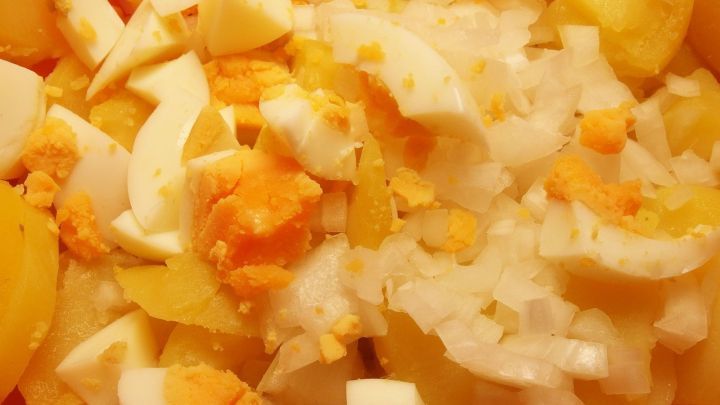 Ein bunter Kartoffelsalat mit gew&uuml;rfelten Kartoffeln und Eiern, frisch zubereitet in einer Sch&uuml;ssel.