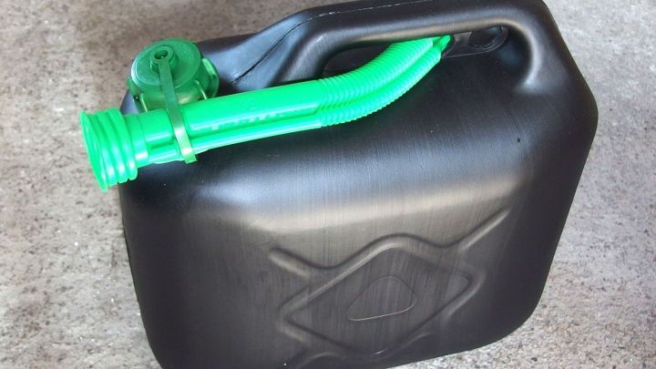 Ein schwarzer Benzinkanister mit gr&uuml;nem Ausgie&szlig;er liegt auf einem Betonboden, bereit zum Bef&uuml;llen oder Ausgie&szlig;en.