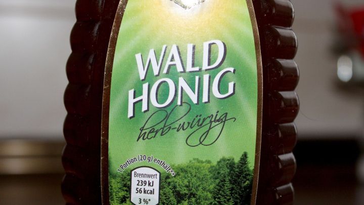 Ein Glas Waldhonig steht auf einer Oberfl&auml;che, bereit zur Anwendung f&uuml;r spr&ouml;de Lippen in einem hellen Raum.