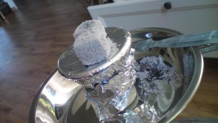 Shishakopf mit Alufolie und zwei gl&uuml;henden Kohlen befindet sich auf einer gl&auml;nzenden Shisha in einem hellen Raum.