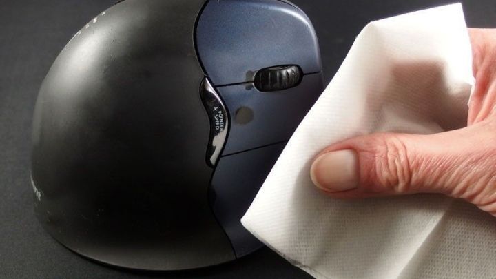 Eine Hand reinigt mit einem Toilettenfeuchttuch eine computerm&auml;&szlig;ige Maus, um Sauberkeit und Hygiene zu gew&auml;hrleisten.