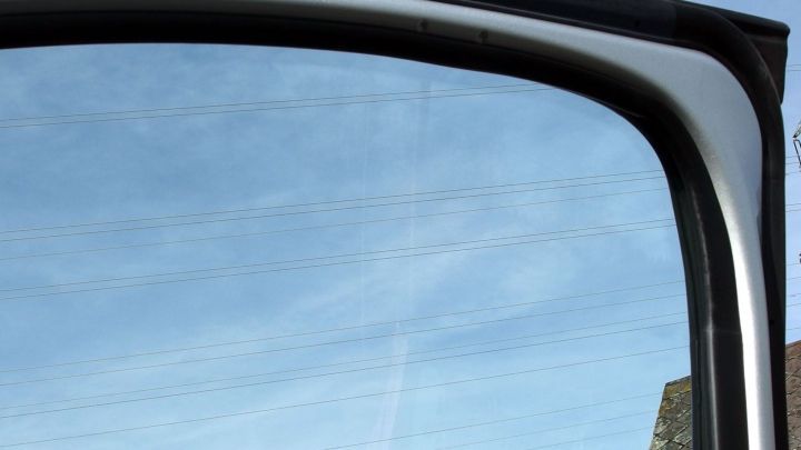 Ein klarer Autoscheibenrahmen spiegelt den blauen Himmel wider, w&auml;hrend die Reinigung die Sicht verbessert.