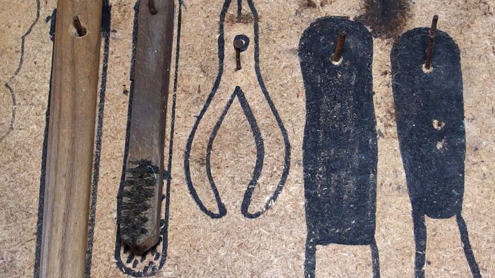 Ein Werkzeugbrett zeigt diverse Handwerkszeuge, die ordentlich angeordnet sind und auf einen Bastelkeller hinweisen.