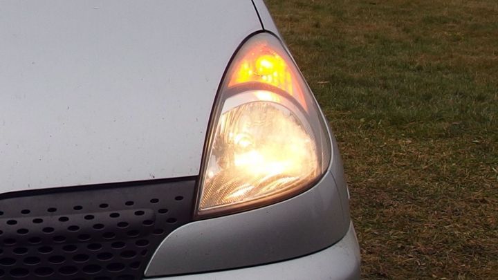 Das Scheinwerferobjekt eines Autos leuchtet orange w&auml;hrend einer Funktionspr&uuml;fung auf einer Wiese.