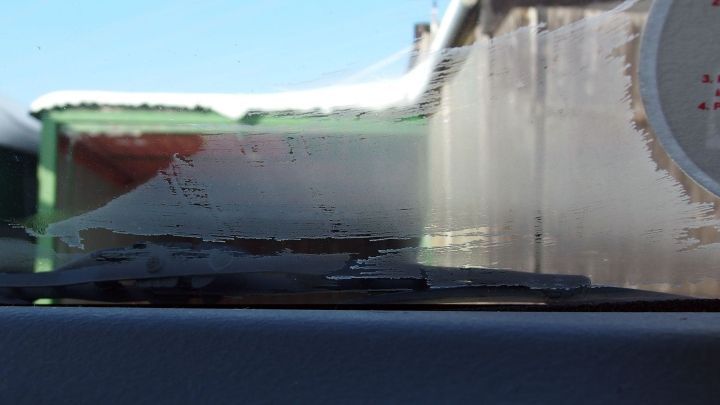 Eine beschlagene Autoscheibe wird von Sonnenschein und W&auml;rme umgeben, w&auml;hrend Schnee auf dem Dach des Fahrzeugs liegt.