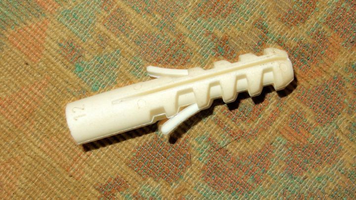 Ein D&uuml;bel liegt auf einem Untergrund, bereit, in por&ouml;se W&auml;nde mit Silikonkleber eingesetzt zu werden.